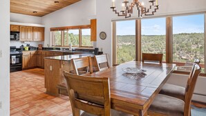 A spacious kitchen with wooden cabinets, a large island, and a dining area with a view of the mountains.