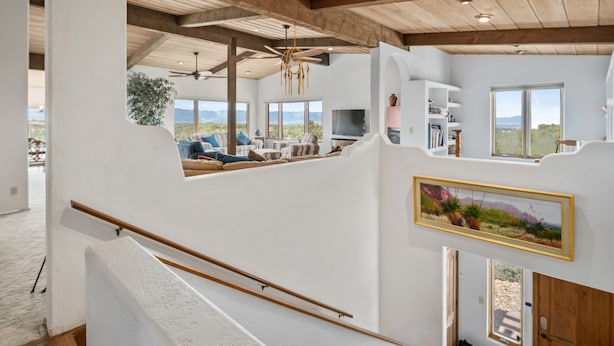 A spacious living area with a high ceiling, wooden beams, a large window, and a view of the mountains.