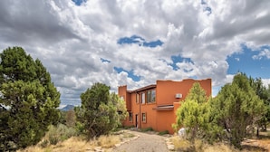 A modern house with a unique architectural style, surrounded by a natural landscape with trees and a clear sky.