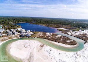 An aerial view of a coastal area with a large body of water, a sandy beach, and residential buildings.