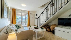 Una sala de estar con un sofá, una mesa de centro, un televisor y una escalera.