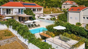 Zona residencial con piscina, paneles solares en los tejados y abundante vegetación.