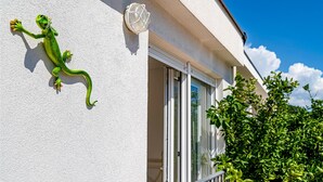 Fachada de edificio con decoración de un lagarto verde, una ventana y una puerta.
