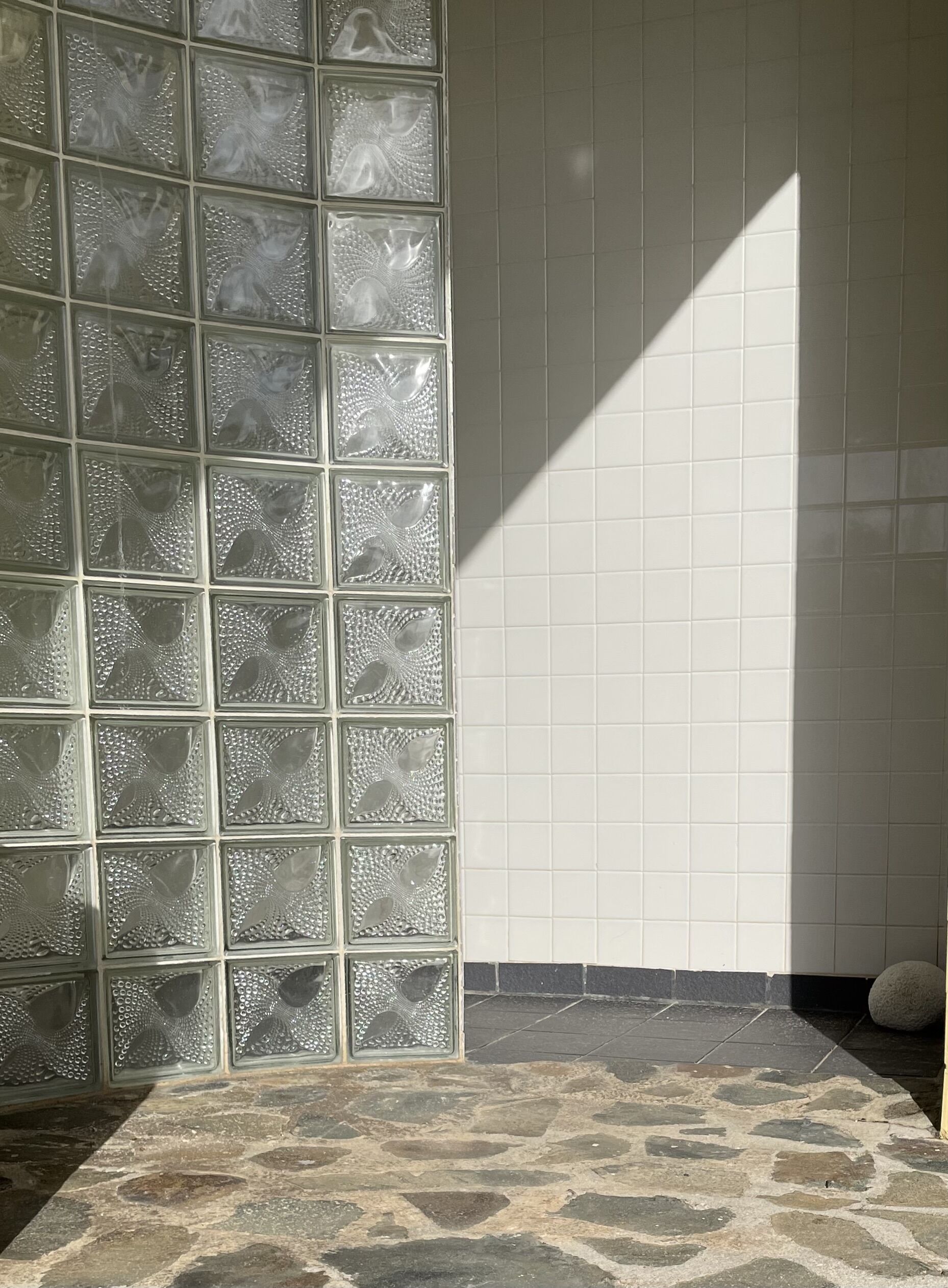 A tiled wall with a geometric pattern and a stone floor.
