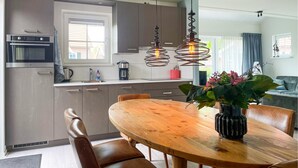 A modern kitchen with a dining area, featuring a wooden table, chairs, and pendant lights. - Buitengoed het Lageveld - 93 (Hoge Hexel)