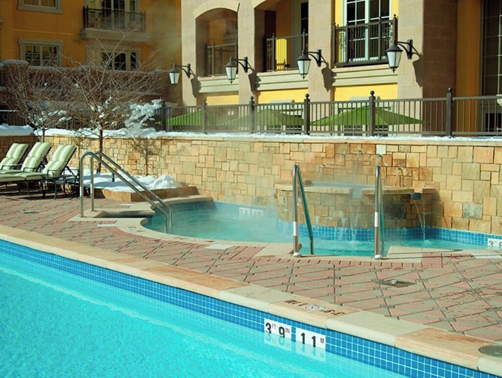 Una piscina con sillas de descanso y un muro de piedra.