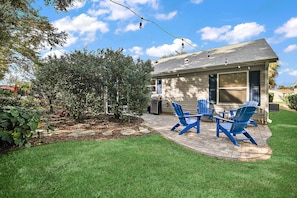 Una casa con un patio que tiene sillas Adirondack azules y un patio de ladrillo.
