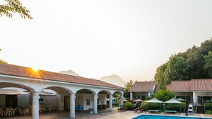 A swimming pool with clear blue water, surrounded by a covered patio area with white columns and tables. - Damyang Hotel (Damyang)