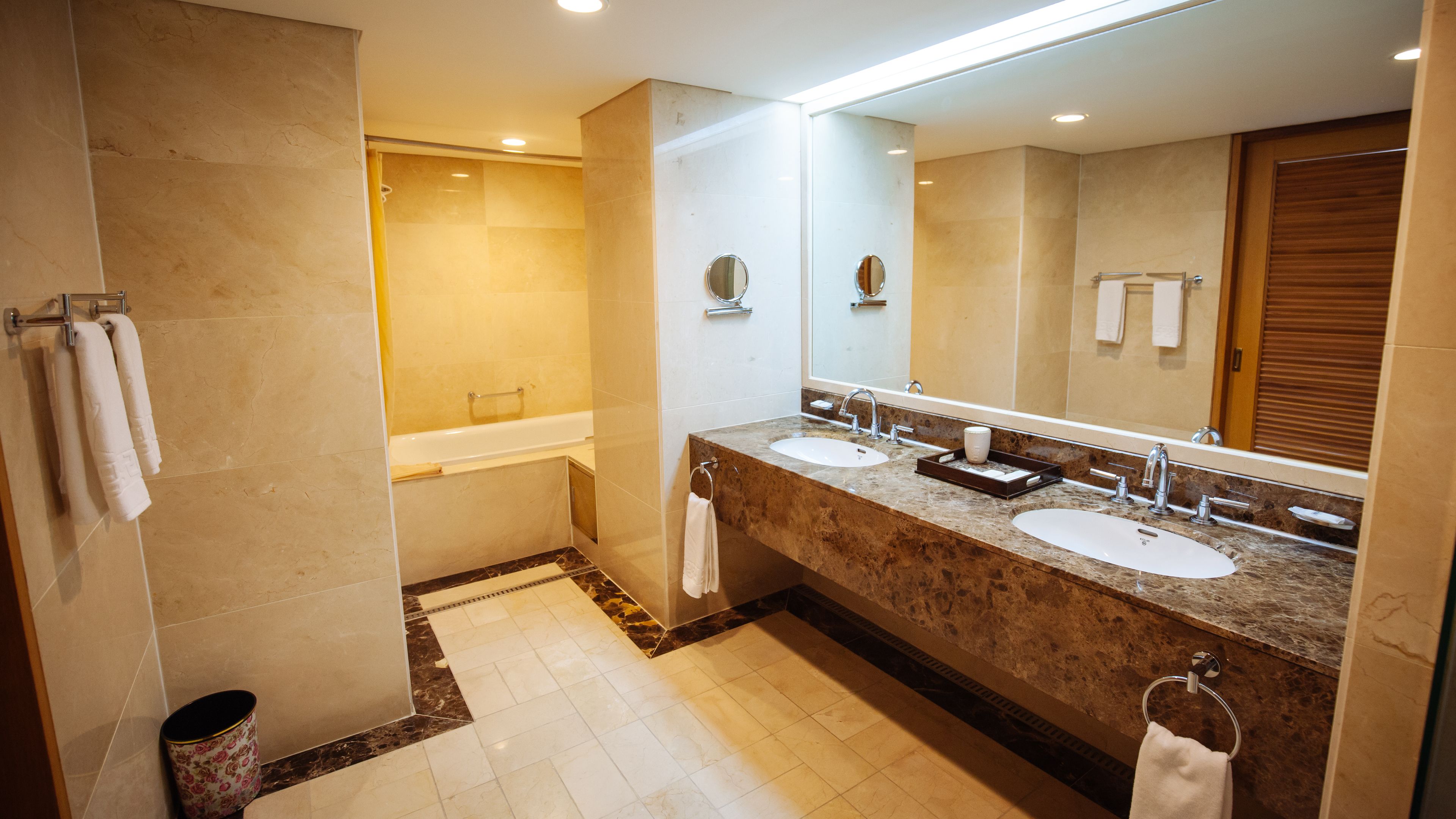 A modern bathroom with two sinks, a large mirror, and a bathtub.