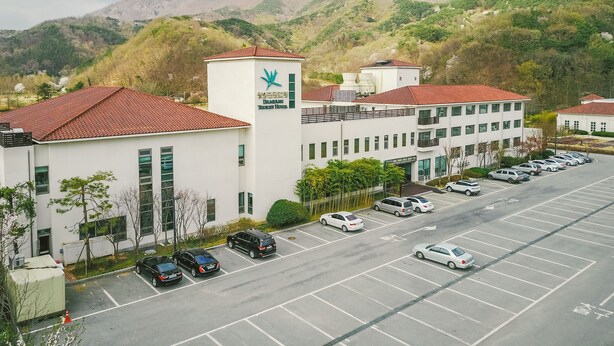 A modern building with a red-tiled roof, a sign for the Danyang Tourist Hotel, and a parking lot with several cars. - Damyang Hotel (Damyang)