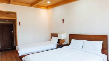 A hotel room with two beds, wooden ceiling beams, and recessed lighting.