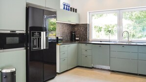 Een moderne keuken met een geïntegreerde koelkast, een koffiezetapparaat en een raam voor natuurlijk licht.