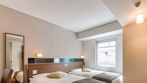 A hotel room with two beds, a mirror, a window, and a ceiling light. - Super Hotel Premier Hakata Station (Fukuoka)