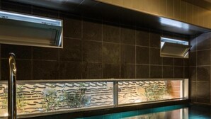 A modern indoor pool area with a clear water surface, a wooden bench, and a stone wall with a decorative panel. - Super Hotel Premier Hakata Station (Fukuoka)