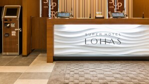 A reception desk at Super Hotel Lohas with a check-in counter, a self-service kiosk, and a patterned curtain backdrop. - Super Hotel Premier Hakata Station (Fukuoka)