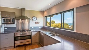 Une cuisine moderne dotée d’appareils électroménagers en acier inoxydable, d’un four encastré et d’une grande fenêtre offrant une vue sur l’extérieur.