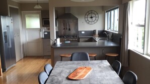 Une cuisine moderne avec un coin repas, un plancher en bois et une grande fenêtre qui laisse entrer la lumière naturelle.