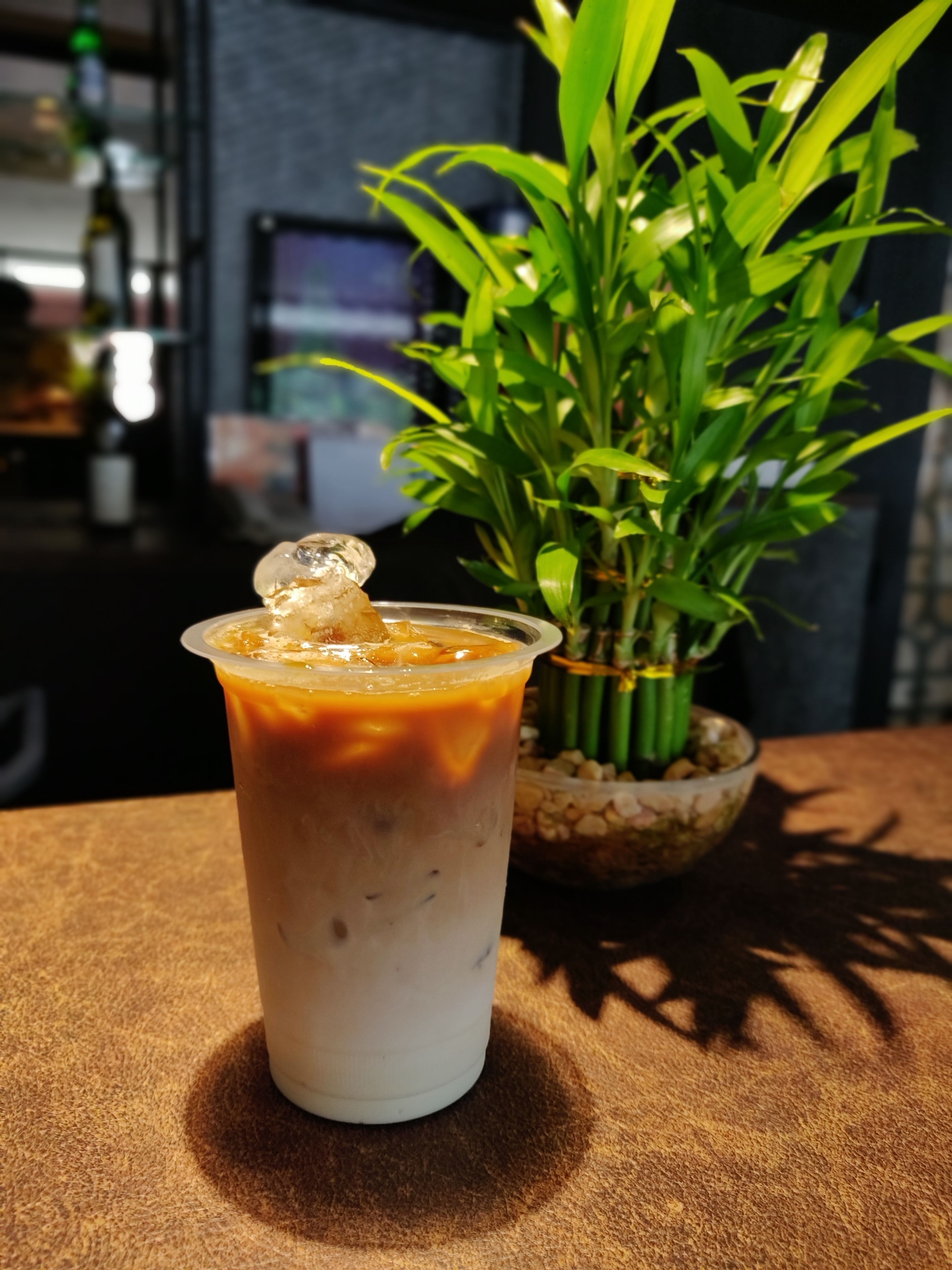 A beverage in a clear plastic cup with a decorative ice cube, placed on a textured surface.