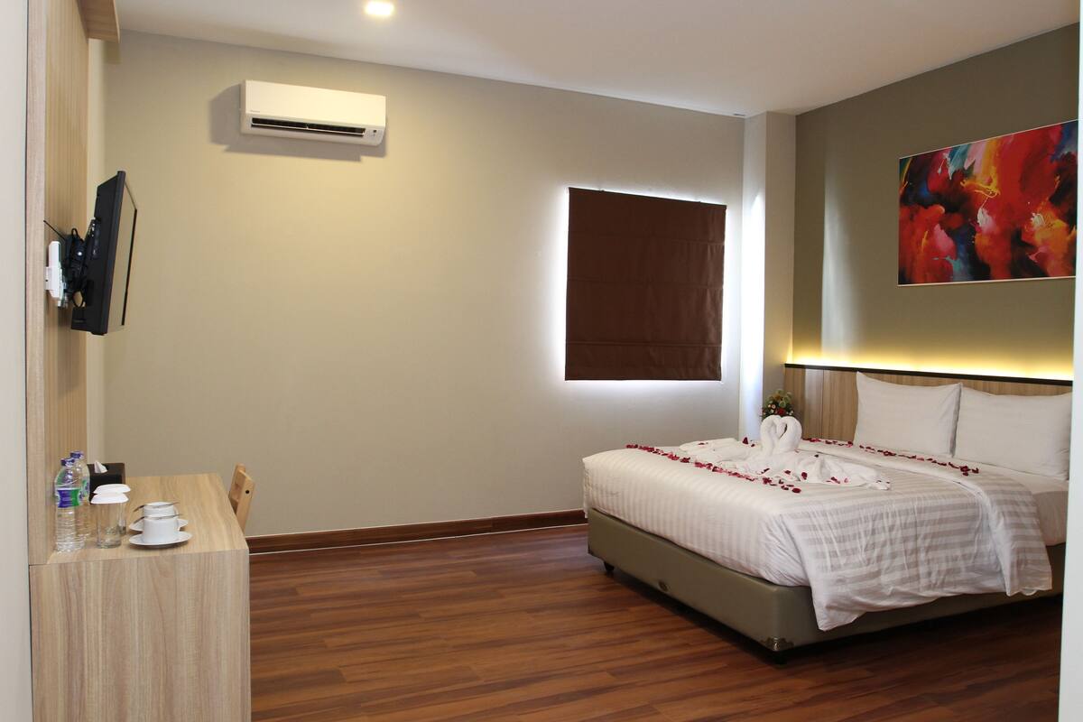 A hotel room with a bed, bedside table, and a mounted TV.