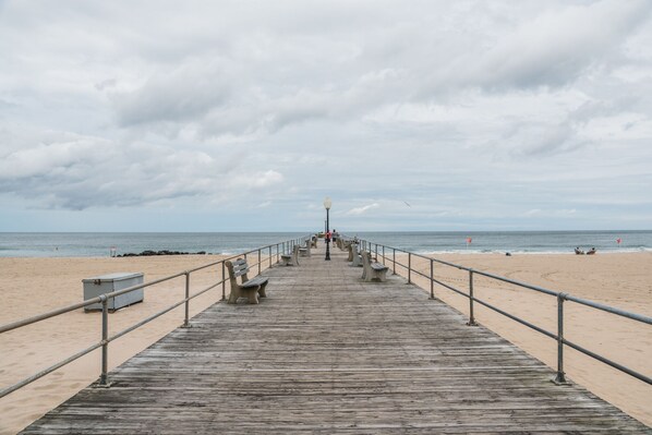 Walk along the beachside boardwalk, lined with benches and a lamp post, to the sandy beach.