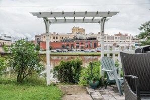 Relax in a serene outdoor setting under a shaded pergola, surrounded by calm waters and lush greenery.