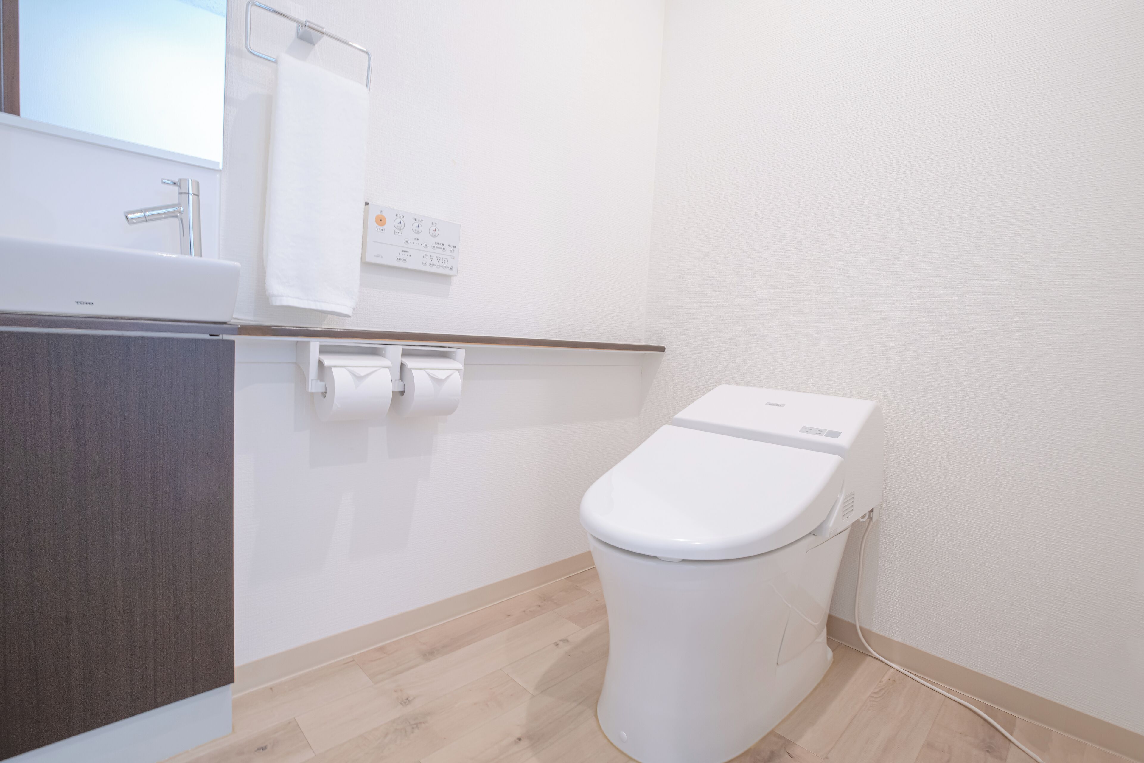 A small, modern bathroom with a white sink, toilet, and towel rack.