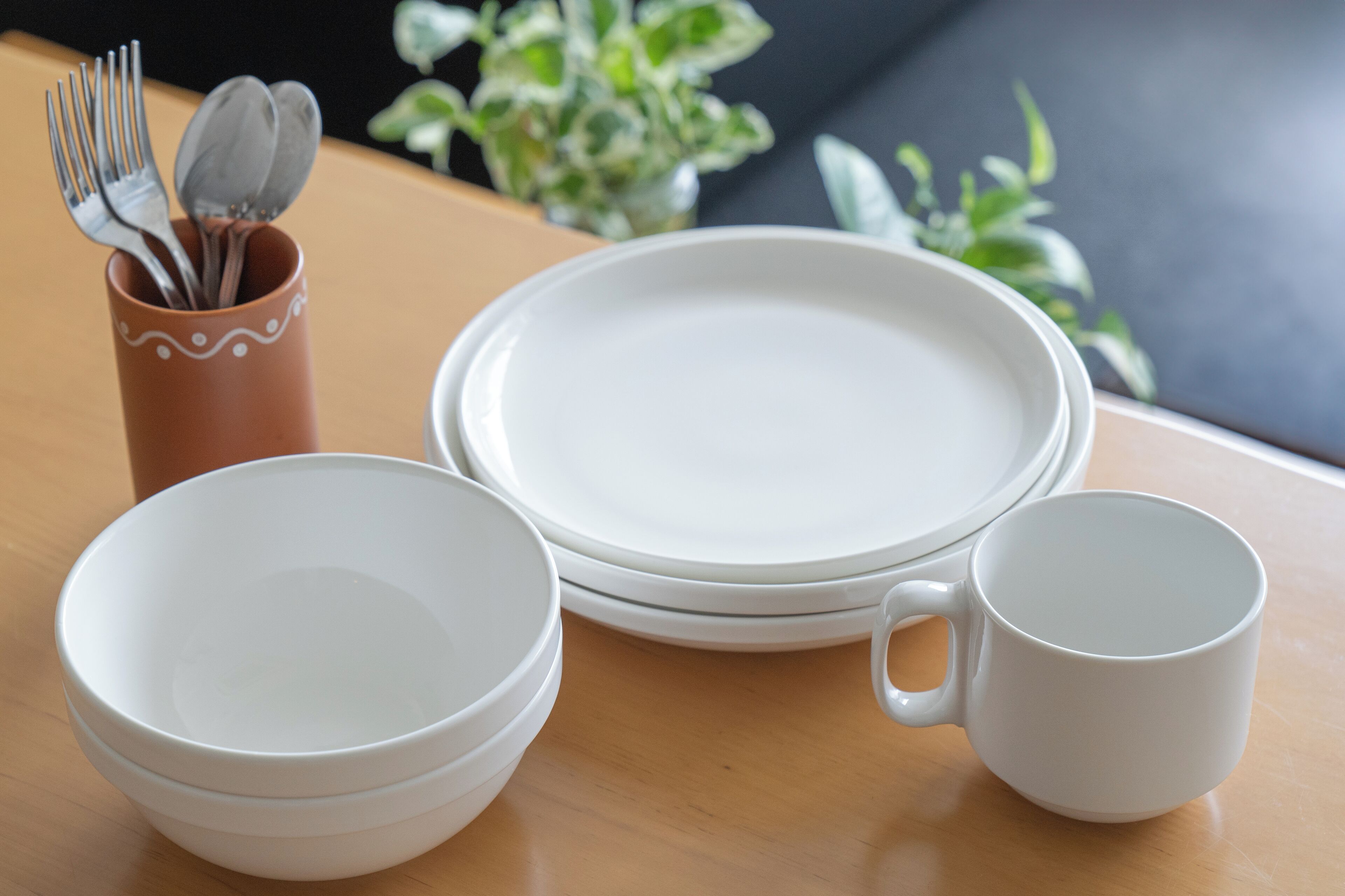 A set of white dishes and a mug on a wooden table.
