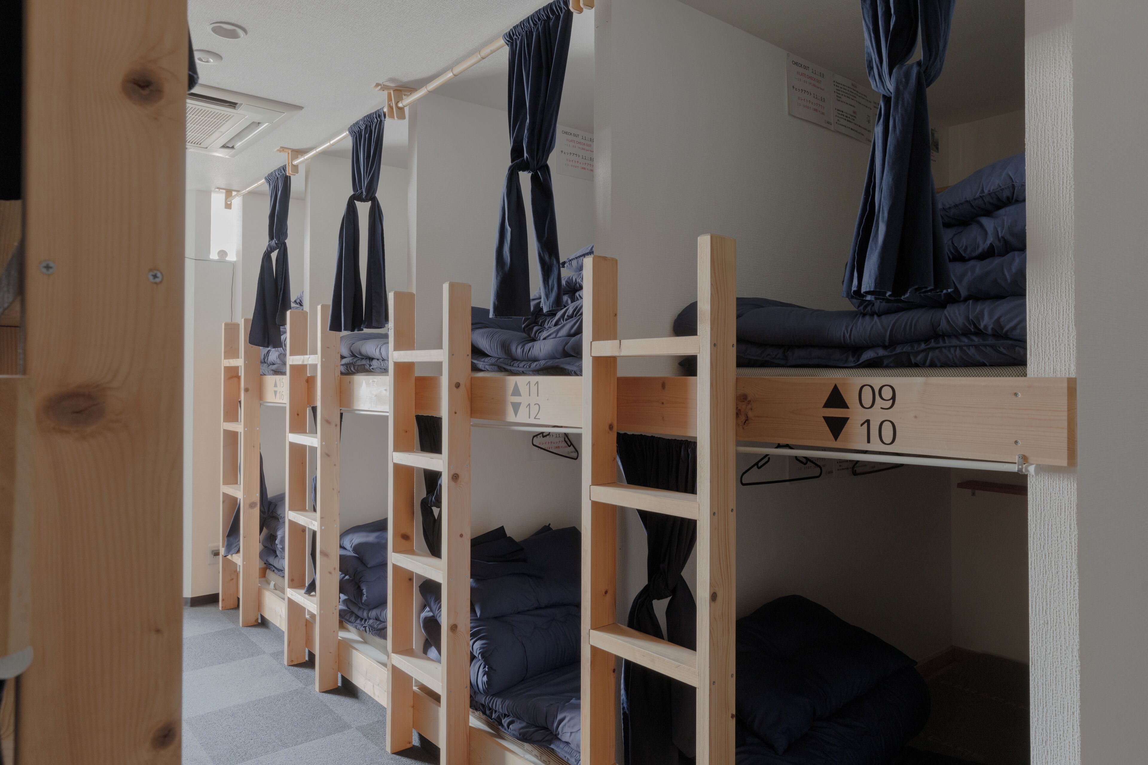 Un dormitorio con literas, barandillas de madera y camas numeradas.