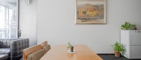 Una sala de conferencias con una mesa de madera, dos sofás, un cuadro y un refrigerador.