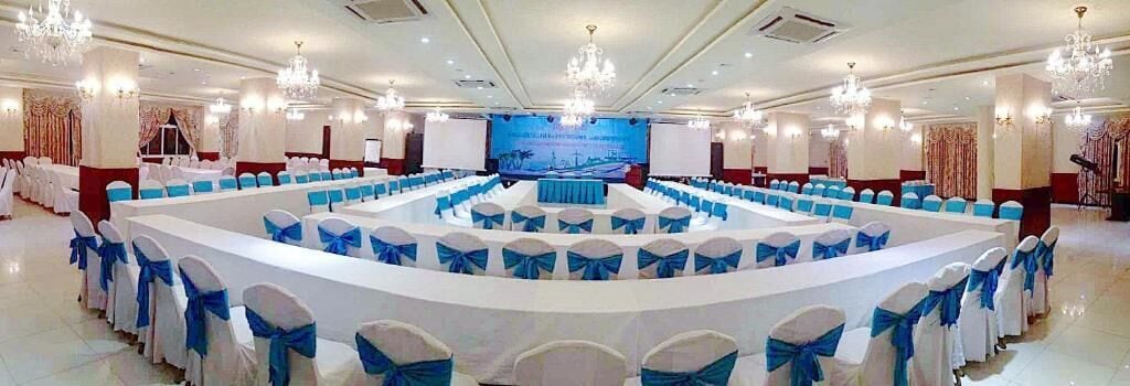 A conference room with a stage, round tables, and chairs.