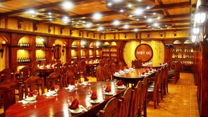 A restaurant with wooden interiors, multiple dining tables, and a prominent sign reading "Viet UC". - Viet Uc Hotel (An Hoi)