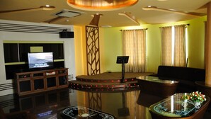 A modern living room with a flat-screen TV, a coffee table, a sofa, and a decorative partition. - Viet Uc Hotel (An Hoi)