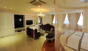 Un salón amplio con televisor de pantalla plana, asientos cómodos y un candelabro.