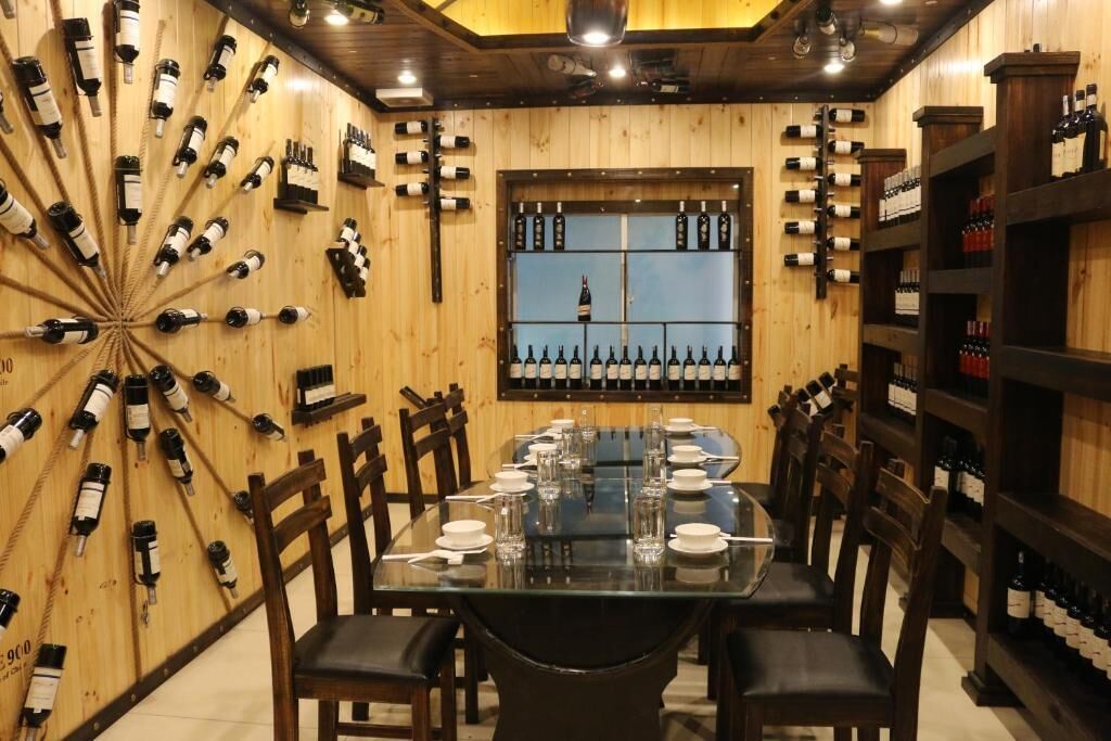 Un restaurante con paredes de madera, una mesa de vidrio y varias botellas de vino exhibidas.