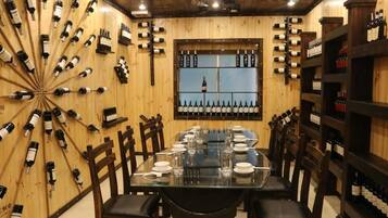 Un restaurante con paredes de madera, una mesa de vidrio y varias botellas de vino exhibidas.