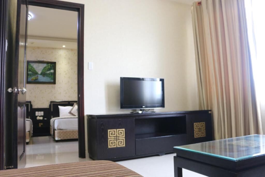 Una habitación de hotel con una cama, un televisor sobre un mueble negro y una mesa de centro de cristal.