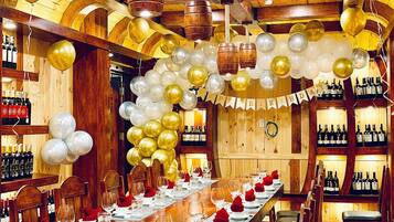 A long dining table set for a celebration with balloons and a banner reading "Happy Birthday".