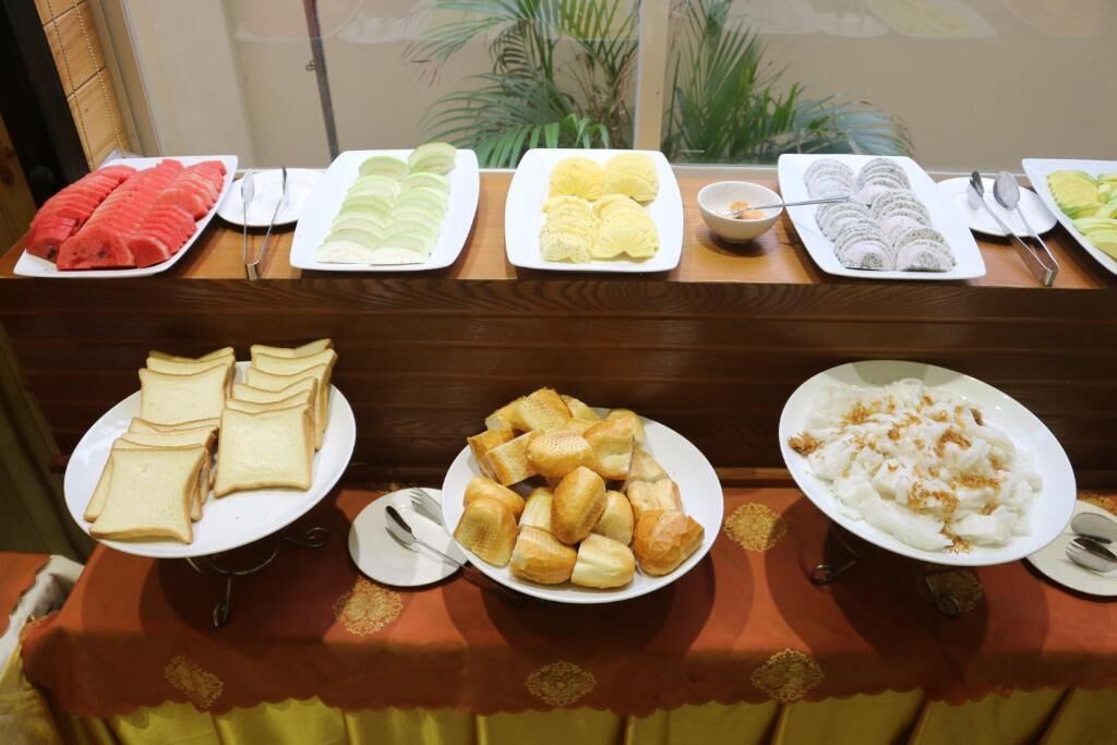 Ein Buffet mit verschiedenen Speisen, darunter Obstsalat, Gebäck und Brot.