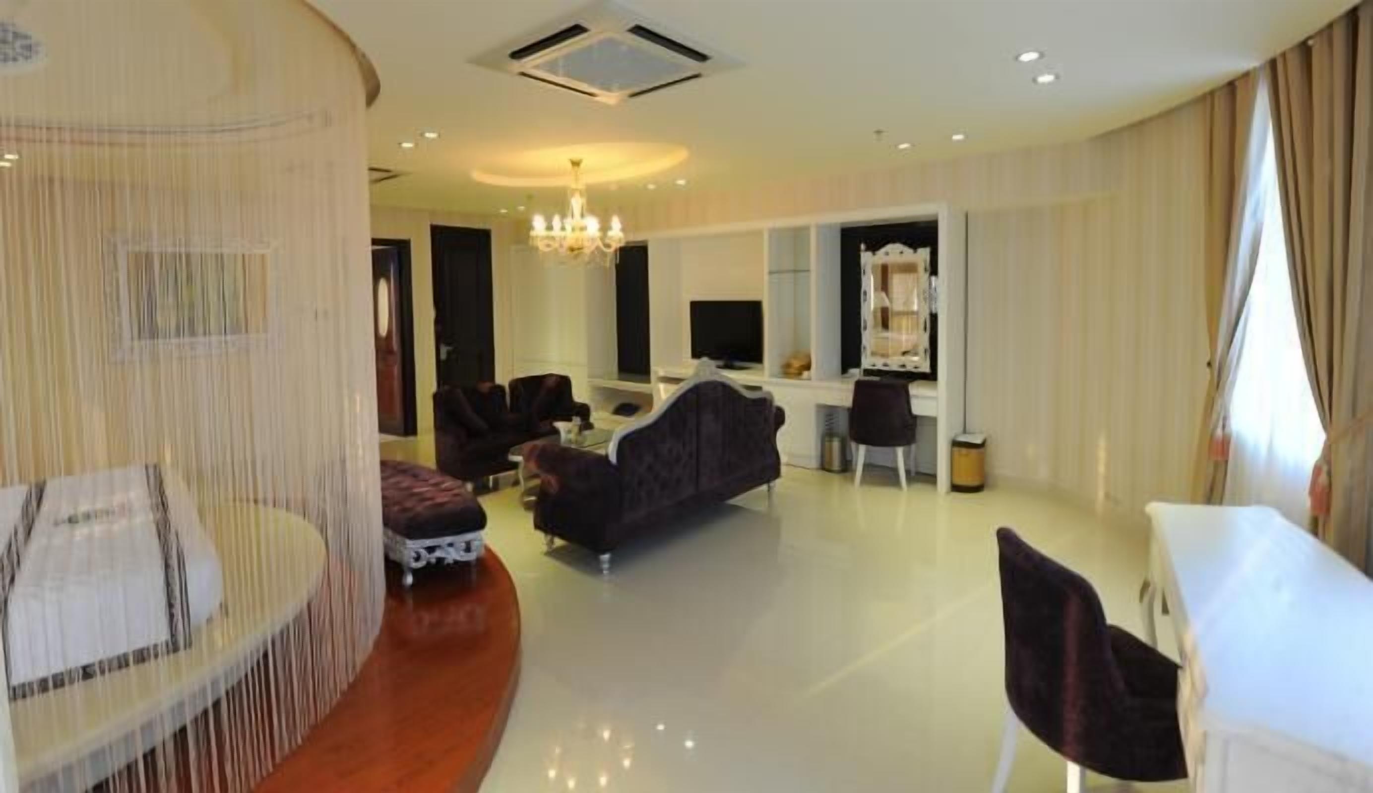 A modern living room with a sofa, chairs, a dining table, and a TV.