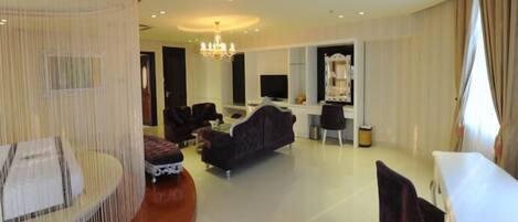 A modern living room with a sofa, chairs, a dining table, and a TV.