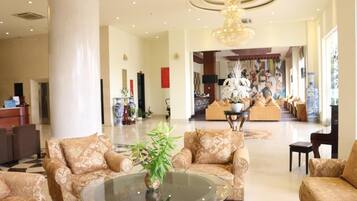 A spacious lobby with a high ceiling, a central chandelier, and a seating area with patterned sofas.