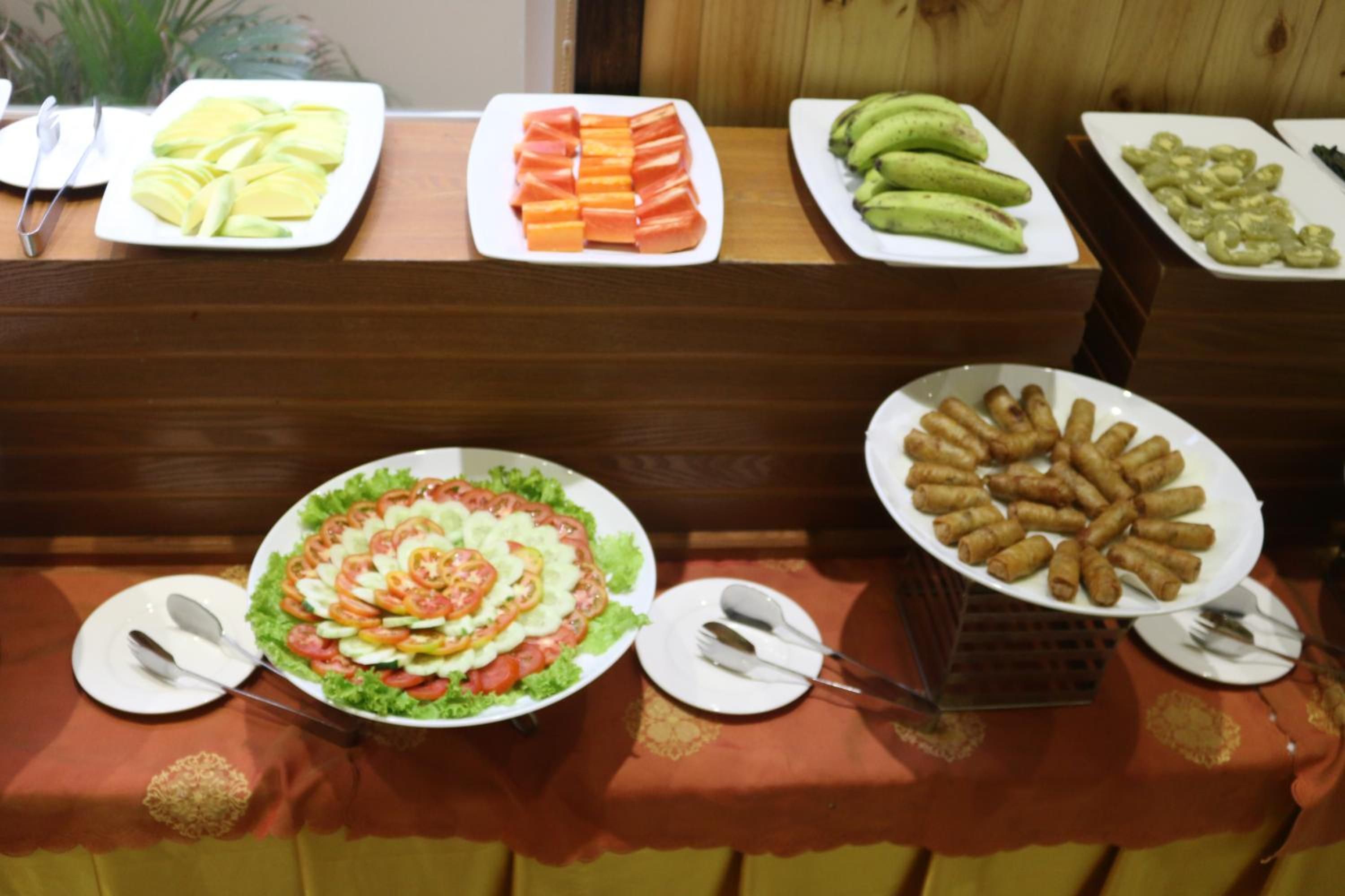 A buffet with various food items including sliced fruits, vegetables, and a salad.
