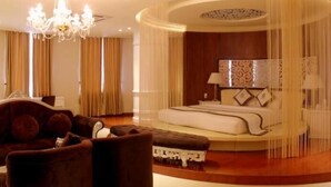 A luxurious bedroom with a large bed, a sitting area with a sofa, and a chandelier. - Viet Uc Hotel (An Hoi)