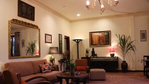 Una sala de estar con sofá, sillones, una mesa de centro, chimenea, un cuadro y una estatua de Buda.