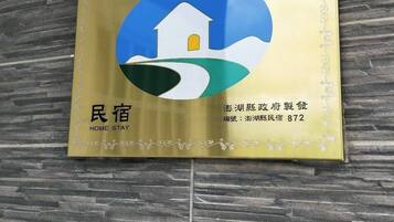 A plaque with a house and green hill graphic, and text indicating 'Home Stay' and a phone number.