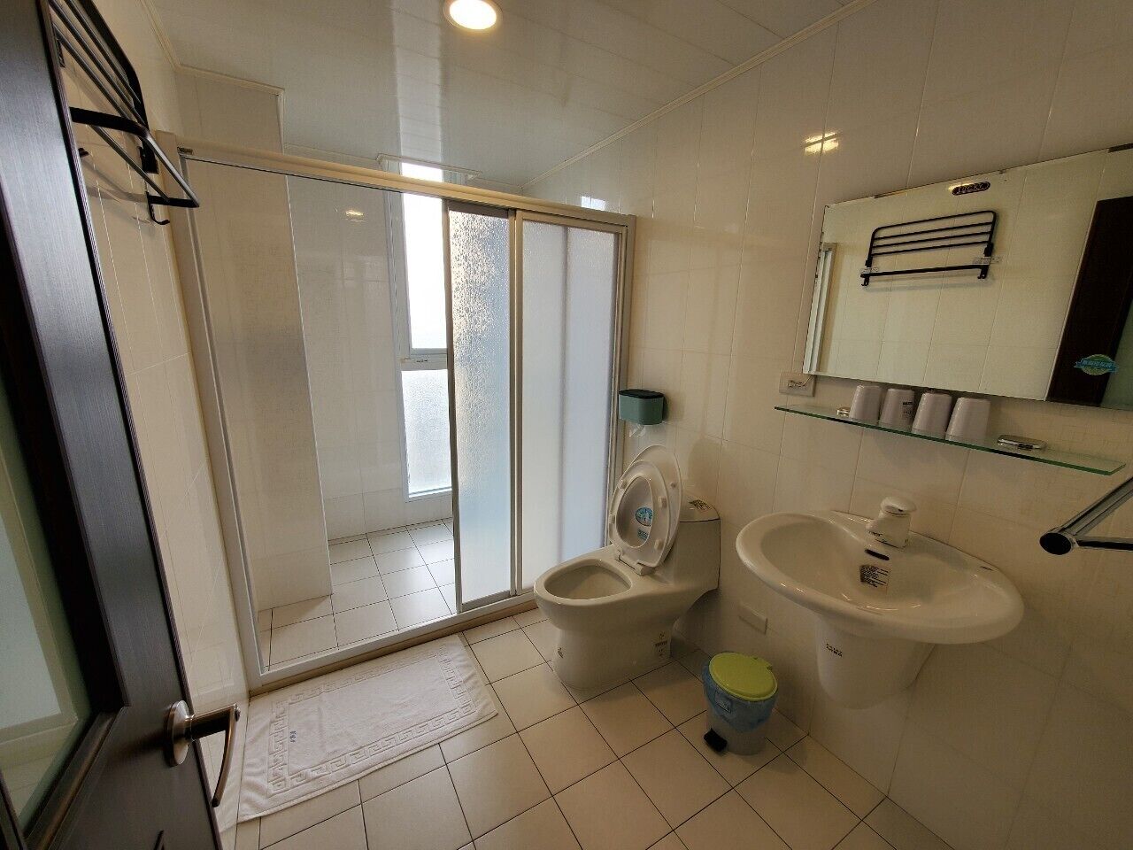 A bathroom with a toilet, sink, and glass shower enclosure.