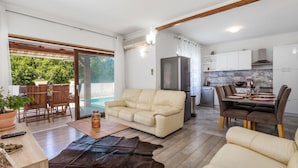 A modern living room with a sofa, a coffee table, and a dining area with chairs and a table set for two. - Nice apartment in Rijeka (Rijeka)