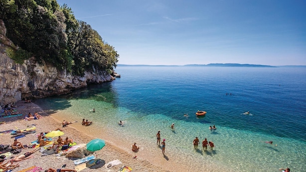 A beach with clear shallow waters, people sunbathing, and a rocky cliff. - Nice apartment in Rijeka (Rijeka)