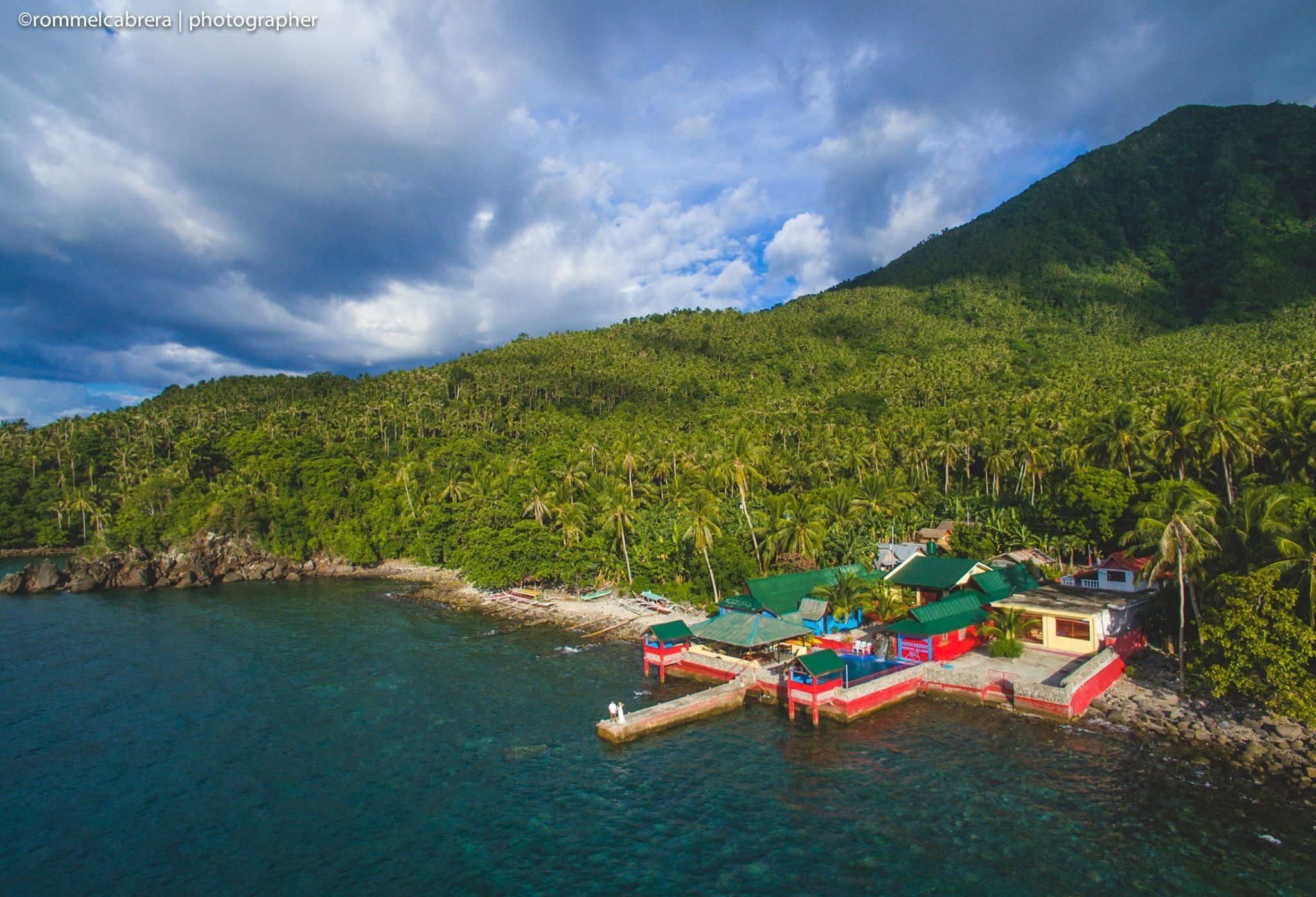 A coastal resort with multiple buildings, a dock, and lush greenery.