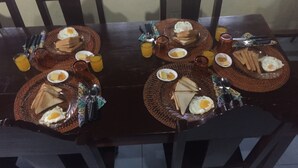 A dining table set with plates of eggs, toast, and juice glasses, surrounded by chairs. - Napo Beach Resort (Maripipi)